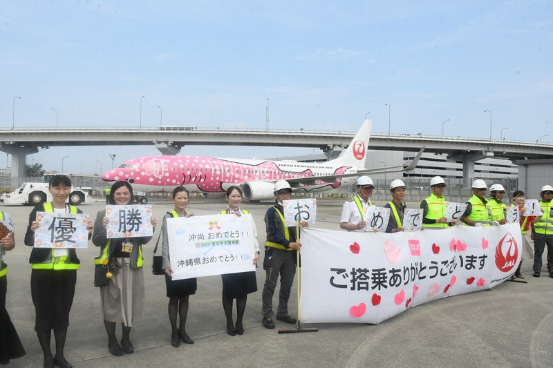 沖縄尚学の選手たちを乗せた航空機の前で、ボードや横断幕を持つ日本航空グループのスタッフ＝関西国際空港で2025年8月24日午前11時2分、中村宰和撮影
