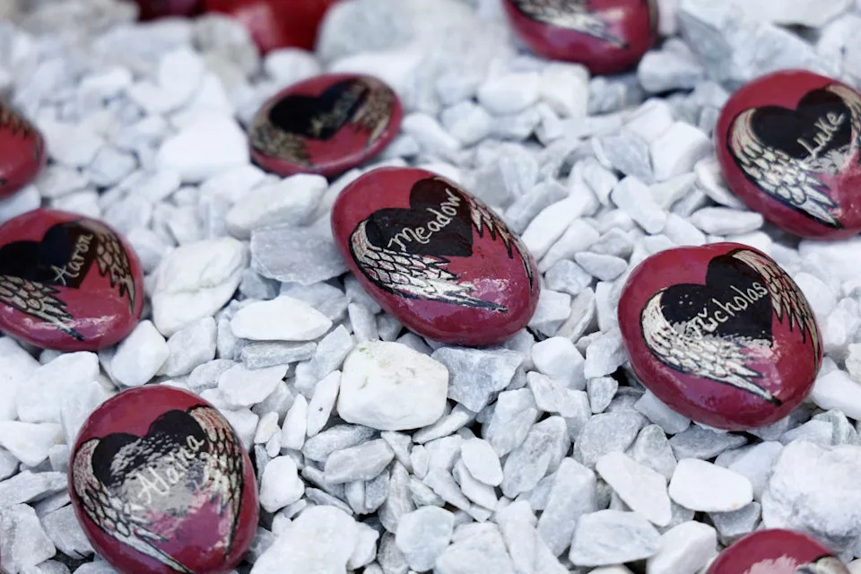 Painted stones with heart design and names like "Meadow" and "Nicholas" on gravel