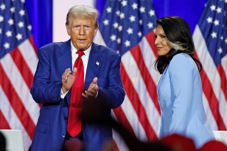 El expresidente de Estados Unidos y candidato presidencial republicano Donald Trump (izq.) aplaude mientras abandona el escenario tras hablar junto a la exrepresentante estadounidense Tulsi Gabbard durante una asamblea municipal en La Crosse, Wisconsin.