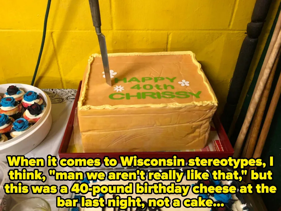 Rectangular cake with "Happy 40th Chrissy" written on top, a knife is stuck in it. It's made of cheese