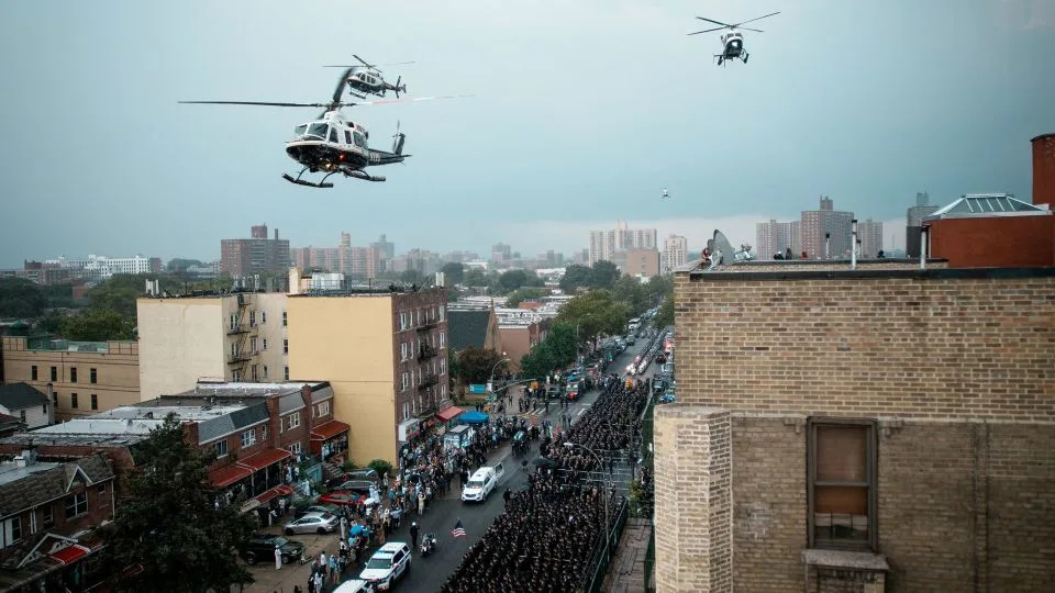 Helicopters fly overhead as Islam's coffin is driven past a wall of loved ones, mourners and law enforcement officers. - Eduardo Munoz/Reuters