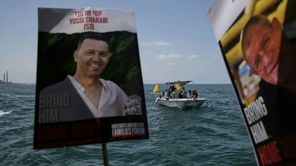 Relatives and supporters of Israeli hostages held by Hamas sail along the coast of Ashkelon on Thursday. - Leo Correa/AP