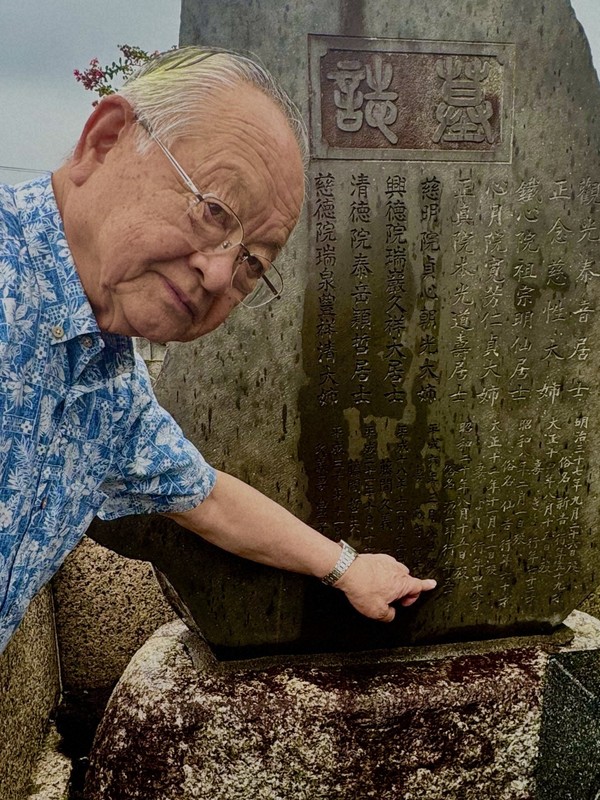 祖父源一郎さんの墓碑を指し示す藤間憲一さん。「昭和二十年八月十五日没」と刻まれていた＝埼玉県熊谷市で2025年8月10日午前9時38分、隈元浩彦撮影