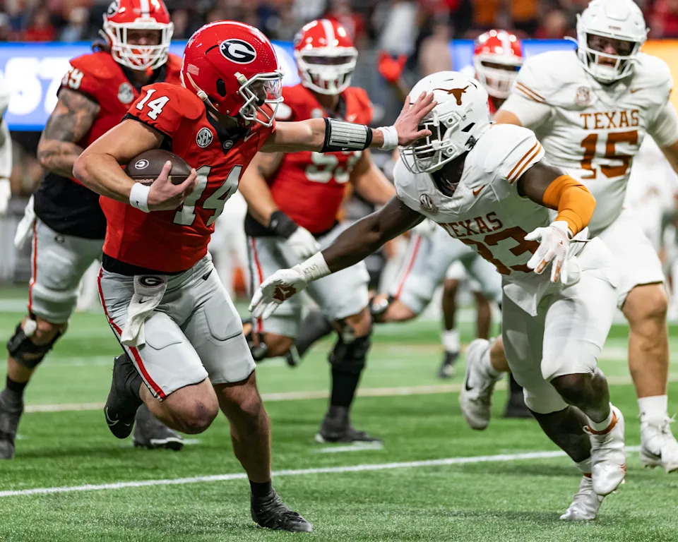 ATLANTA, GEORGIA - DECEMBER 7: Gunner Stockton #14 of the Georgia Bulldogs tries to avoid a tackle by David Gbenda #33 of the Texas Longhorns during a game between the Georgia Bulldogs and the Texas Longhorns at Mercedes-Benz Stadium on December 7, 2024 in Atlanta, Georgia. (Photo by Steve Limentani/ISI Photos/Getty Images)