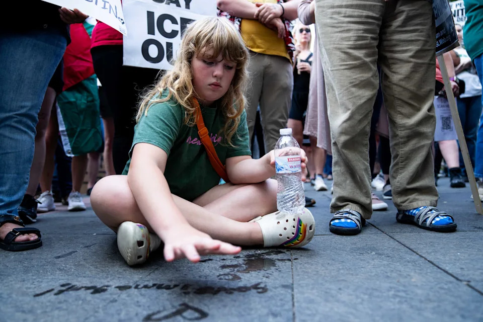 Eloise Moyle, 10, writes "Save Immigrants" with water from her bottle during a rally June 10 in Des Moines.