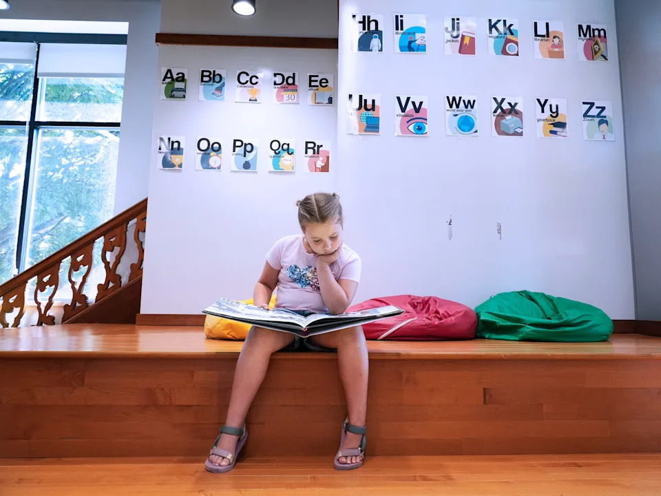 Former first-grader Josie, 7, reads in the library at Lincoln Elementary in Wauwatosa during the summer school program.