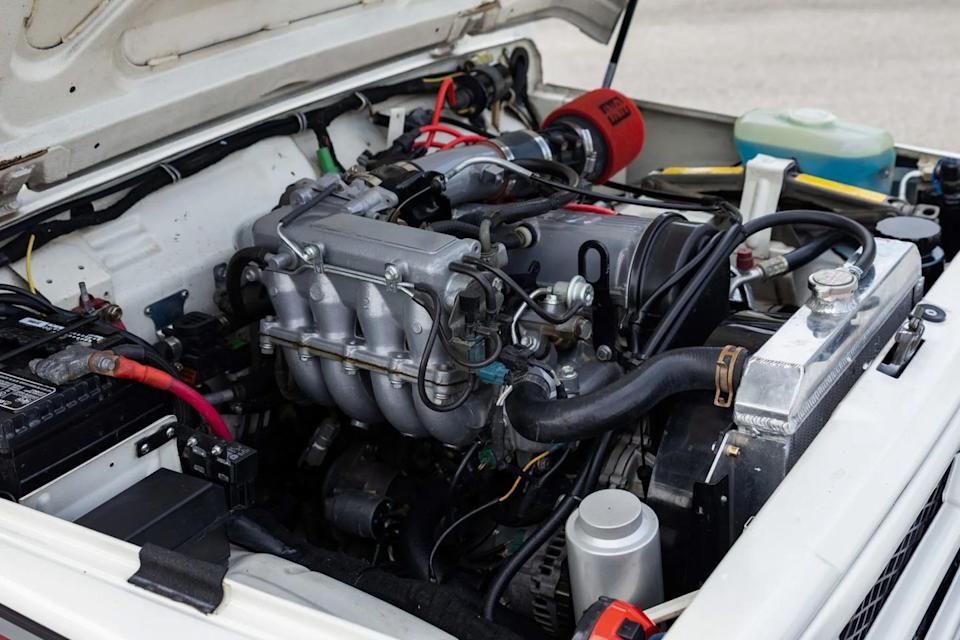 engine bay view with open hood showing intake manifold, battery, and aftermarket air filter.