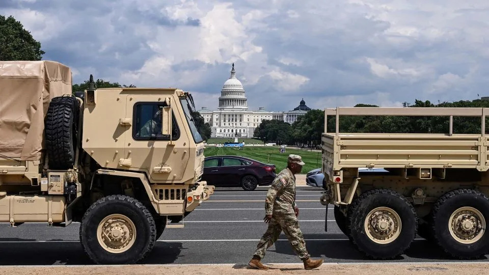 A member of the US National Guard walks past military vehicles on the National Mall in Washington, DC, on August 14, 2025. - Alex Wroblewski/AFP/Getty Images