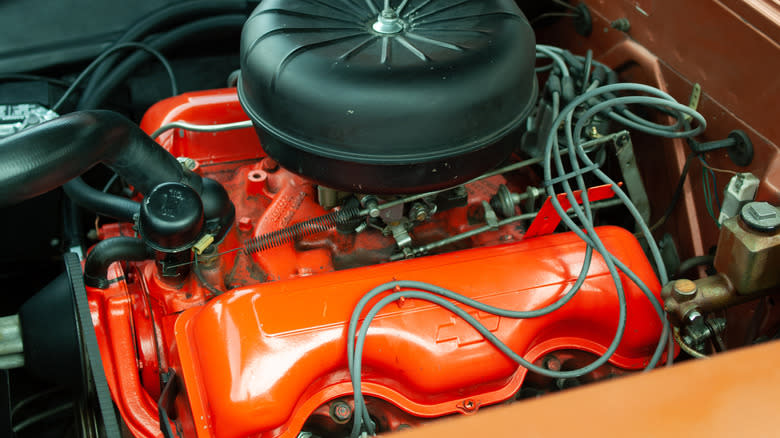 A red Chevrolet 348 W-series big block V8 with black air cleaner under the hood of a vintage Chevy