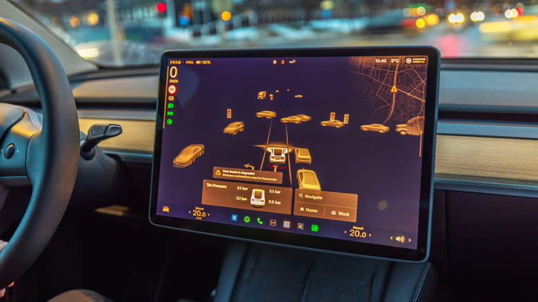 Tesla Model Y interior with touchscreen displaying autopilot visualization, detecting vehicles, traffic lights and surroundings at night. Sweden.