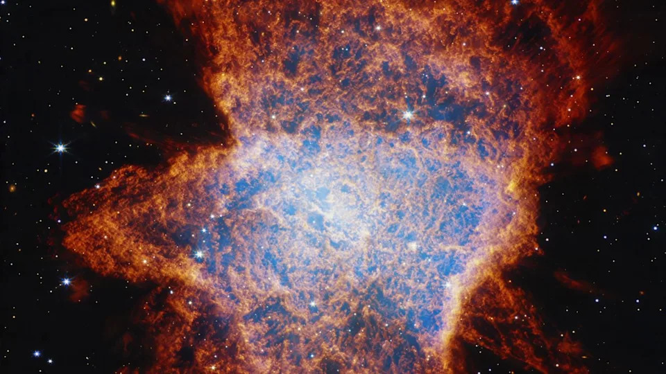 A glowing nebula of blue and red and white lights gleams in the darkness of outer space.
