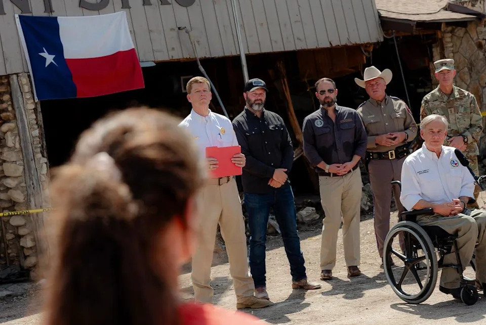 Governor Greg Abbott listens to Courtney Calhoun, a Kerr County resident and volunteer, during a press conference in Hunt on Tuesday July 8, 2025.