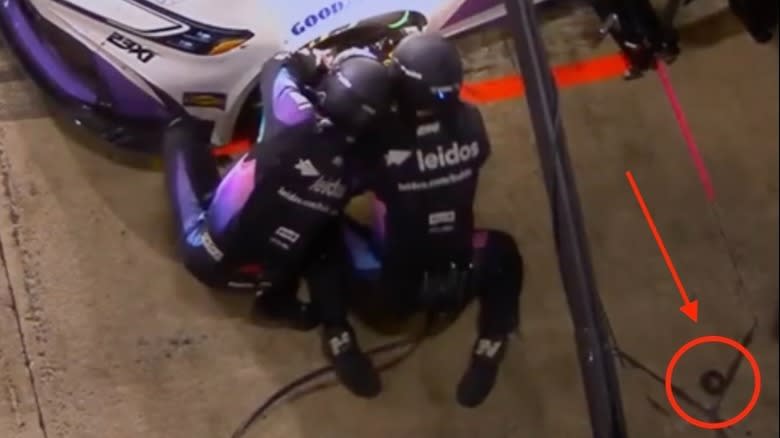 Wheel nut on the ground behind the unaware pit crew