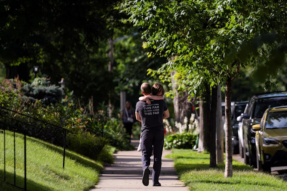 A father carries his daughter, as they walk towards their vehicle after a shooting at Annunciation Church, which is also home to an elementary school, in Minneapolis, Minnesota, August 27, 2025.
