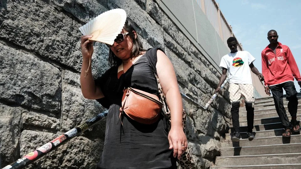 A woman shades herself from the sun as she tries to keep cool along the Brooklyn Bridge during a heat wave. - Spencer Platt/Getty Images