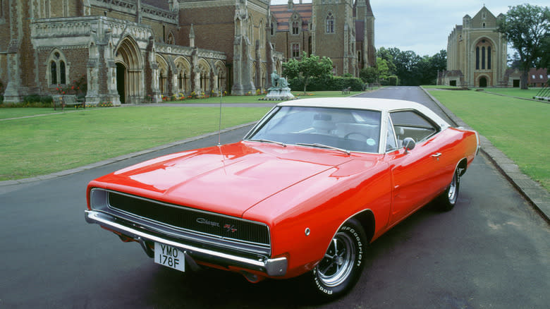 A bright red Dodge Charger R/T posed on the driveway of an old building.