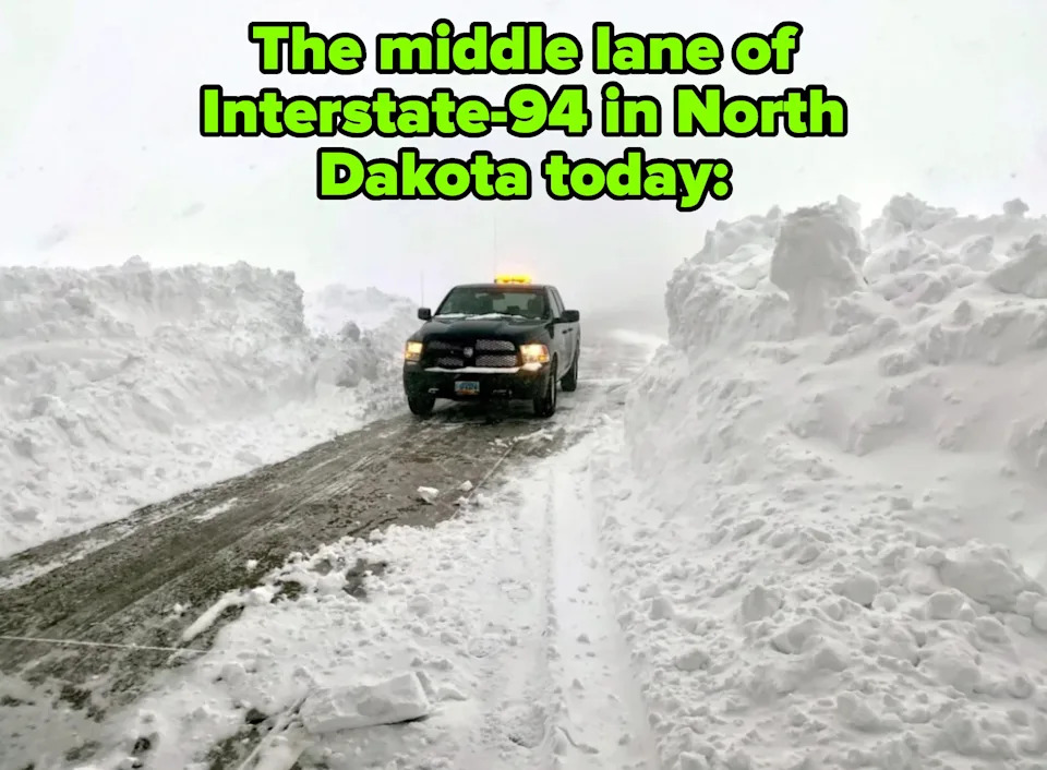 Truck plows through deep snow on a narrow road, surrounded by towering snowbanks. Caption: "The middle lane of Interstate-94 in North Dakota today"