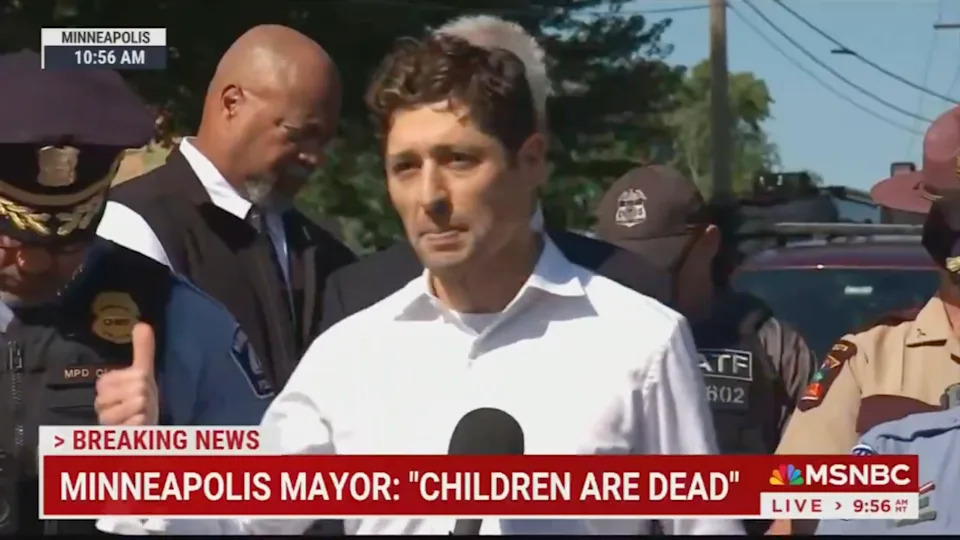 A man speaks at a press conference with police officers nearby. Breaking news ticker says, "Minneapolis Mayor: 'Children are dead.'"