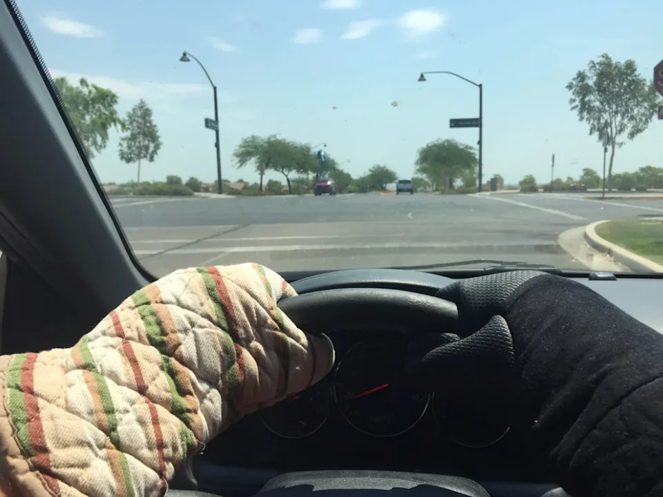Person driving with oven mitts on the steering wheel, viewed from behind