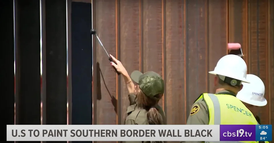 Person in uniform painting border wall with two others watching; caption reads: “U.S. to paint southern border wall black” with CBS19 News watermark