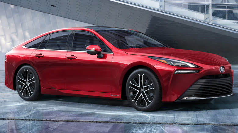 A red 2024 Toyota Mirai in front of a modern building