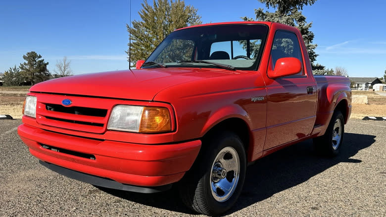 A red 1993 Ranger Splash single cab stepside parked in front of a tree