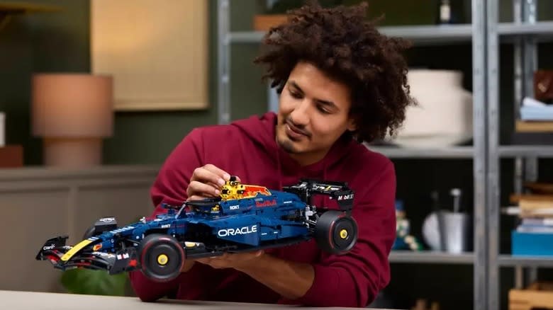 A man in a maroon hoodie admires a blue Oracle Red Bull Racing RB20 F1 Car