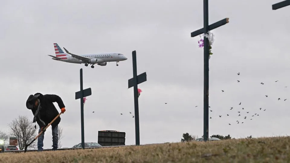 A plane lands behind a memorial to those killed in the midair collision at Reagan National Airport in Arlington, Virginia. - Roberto Schmidt/AFP/Getty Images