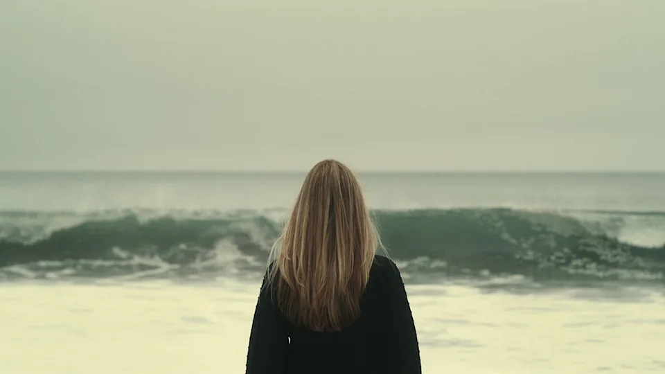 Denise Huskins with her back turned looking at the ocean.