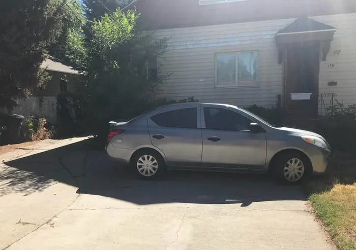 Reddit post showing a car parked in a residential driveway, with a caption about it being left there during a 4th of July parade due to street closures