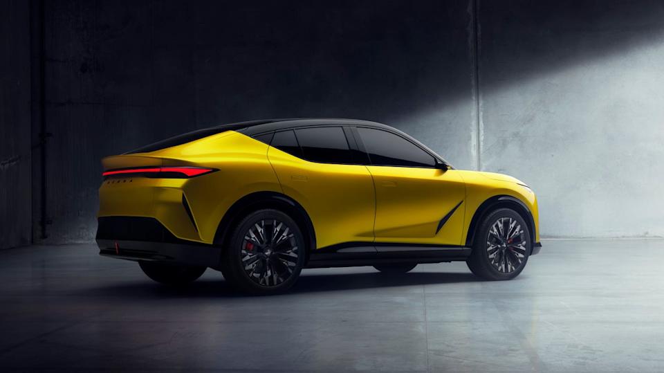 rear three quarter view of yellow suv with black roof, vertical taillights, and multi spoke wheels in dimly lit room.