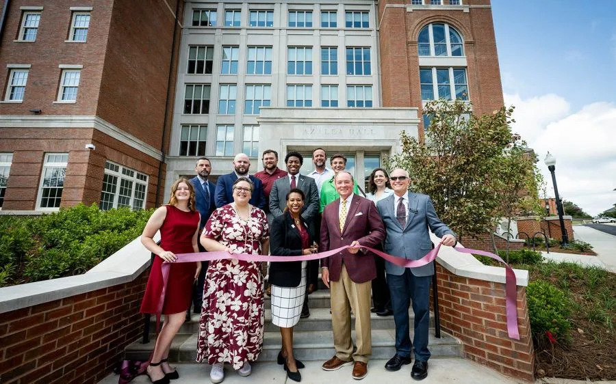 Celebrating a ribbon cutting ceremony for Azalea Hall, Mississippi State’s newest and largest student residence hall, are from left, front row: Julia Bryant, Residence Hall Association president; Vice President for Student Affairs Regina Hyatt; Executive Director of Housing and Residence Life Dei Allard; MSU President Mark E. Keenum; Luckyday Foundation Chair Jamie Houston; back row: James Jankowski, resident district manager for MSU Dining Services; P.J. Pearson, HPM project manager; Ches Fedric, MSU director of Planning, Design and Construction Administration; Student Association President Cameron Cummings; Saunders Ramsey, executive director of MSU Campus Services; Jule Markle, Wier Boerner Allin Architecture principal and senior project architect; and Gwynn Zivic, Mackey Mitchell Architects lead designer. (Photo by Grace Cockrell via Mississippi State University)
