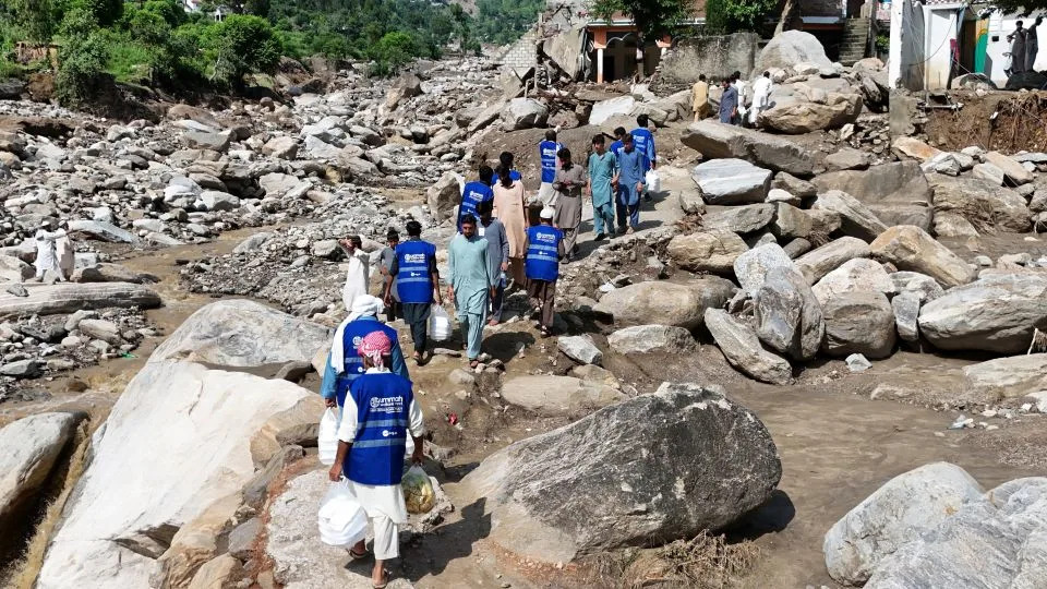 In this aerial picture, volunteers carry aid for residents, after flash floods hit Buner district in northern Pakistan's mountainous Khyber Pakhtunkhwa province on August 18, 2025. - Abdul Majeed/AFP/Getty Images