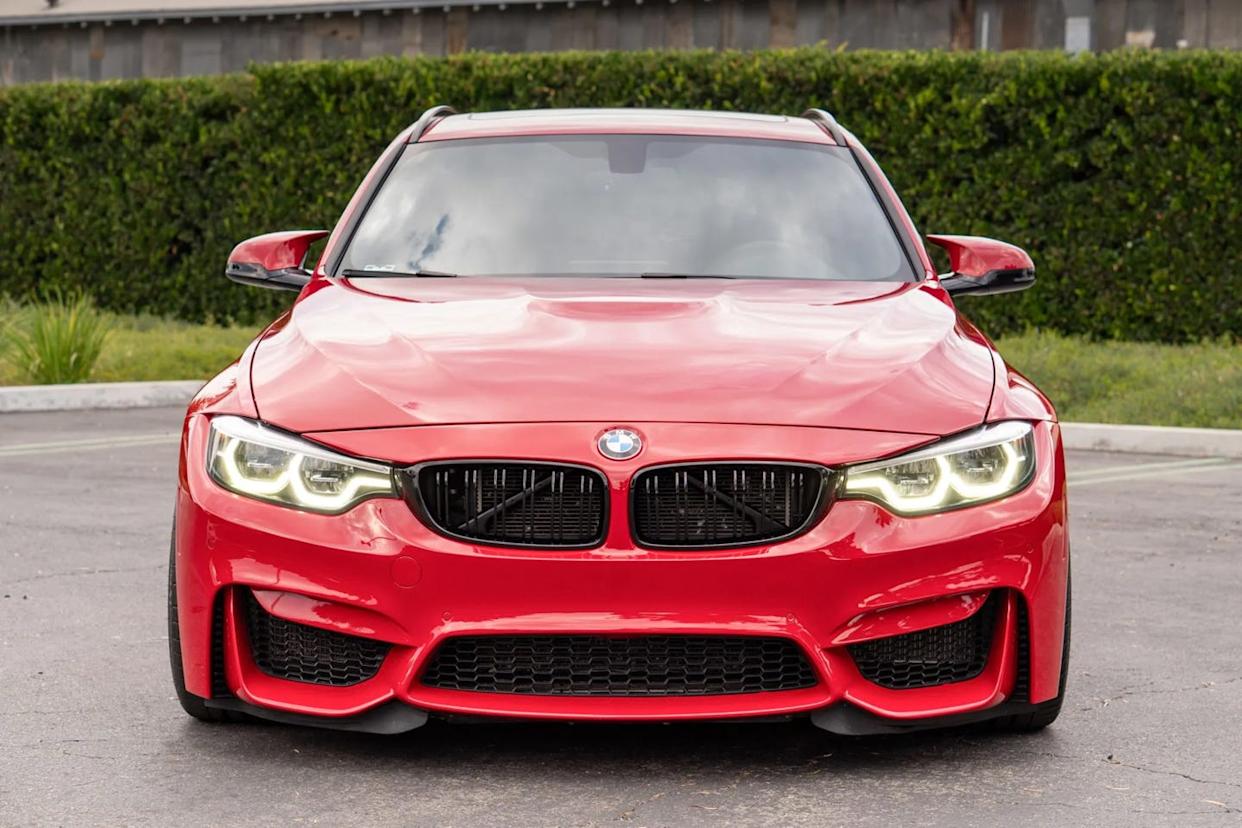 front view of red station wagon with led headlights, dual kidney grille, and wide lower air intake parked on pavement.