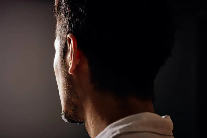 A person with short hair is seen from behind, looking towards the light