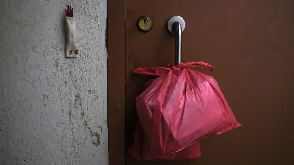 Donated items that Ms. Sze delivers to residents hang from the door of a subdivided unit in Sham Shui Po, Hong Kong, on July 3, 2025. - Catherine Phillips/CNN