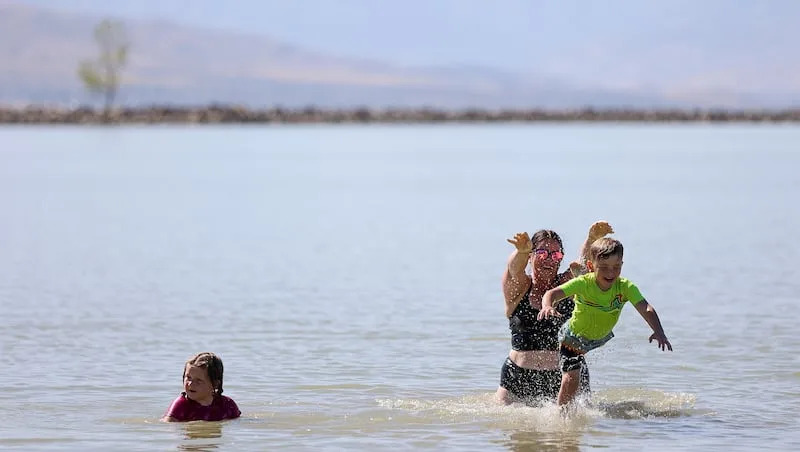 Breann Webb throws Hudson Webb into the water as Sailor Webb swims at Utah Lake State Park in Provo on Monday, July 28, 2025.