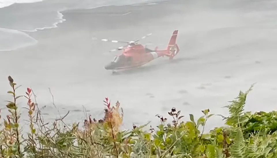The helicopter lands on the beach after the rescue.
