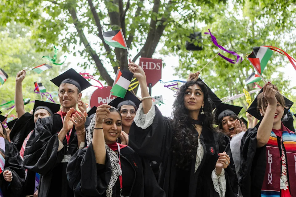 Graduates celebreate and wave Palestinian flags outside in their graduation caps and gowns (Libby O'Neill / Getty Images file)