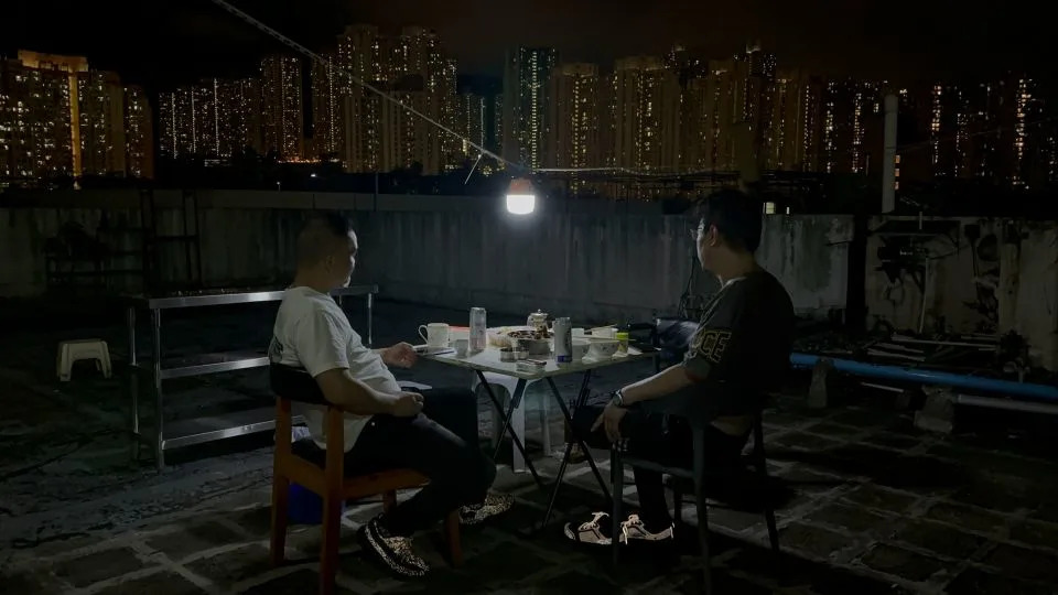 Residents of a rooftop structure atop an industrial building in Kwun Tong, Hong Kong eat dinner on July 8, 2025. - Jared Formanek/CNN