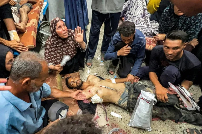 People gathered around one of the people shot while waiting for aid trucks entering Gaza on Thursday (Bashar TALEB)