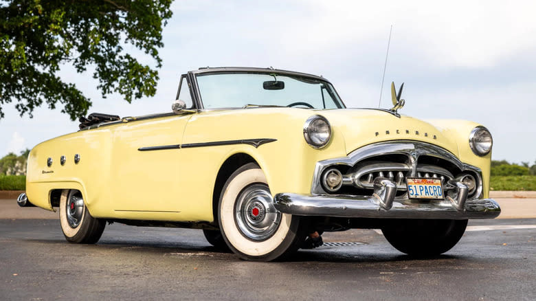 A cream 1950 Packard convertible parked in front of a tree