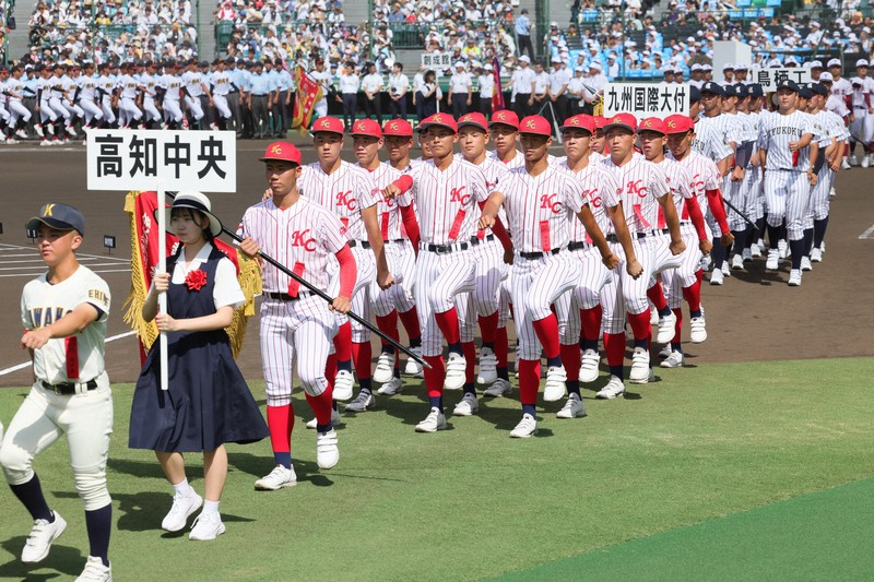 赤の縦じま仕様のユニホームで入場行進する高知中央の選手たち＝阪神甲子園球場で2023年8月6日、吉田航太撮影