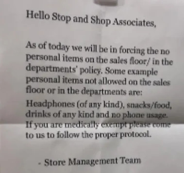 Notice on wall about store policy prohibiting personal items, food, drinks, and headphone use on the sales floor