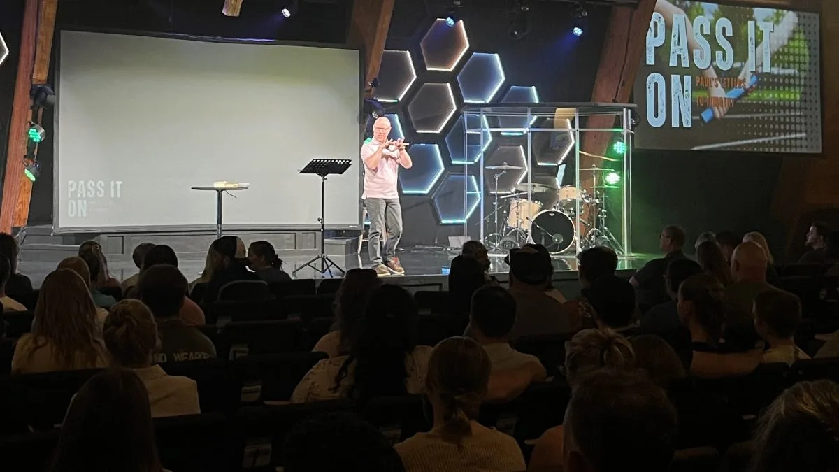 A man standing on stage preaching to his congregation.