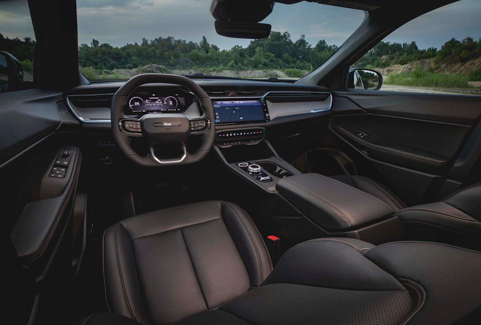 interior view from front seats showing steering wheel, digital instrument cluster, center screen, and black leather seats.