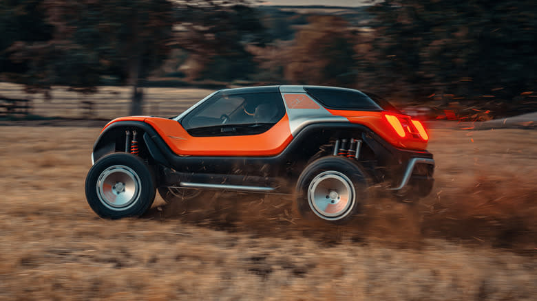 rear three-quarters shot of the orange and silver LFG ripping through a grass field