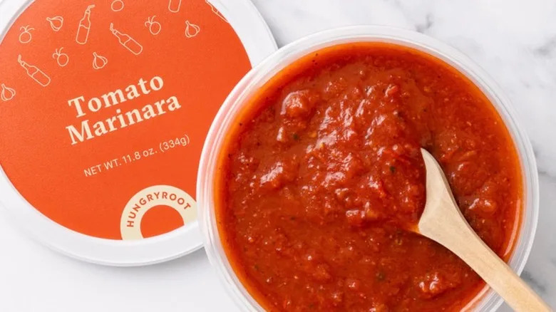Open container of Hungryroot marinara with a wooden spoon resting in the sauce