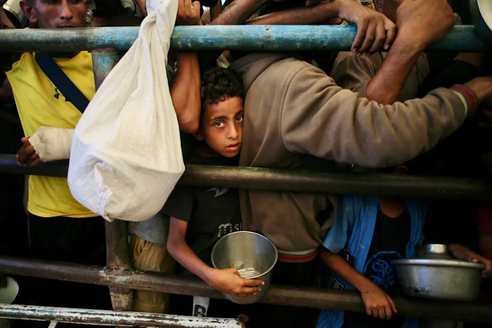 A Palestinian boy waits for a meal at a charity kitchen in the Mawasi area of Khan Yunis in the southern Gaza Strip.