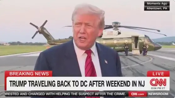 Person speaking to the media on an airport tarmac; a helicopter is seen in the background. News text: "Trump traveling back to DC after weekend in NJ."